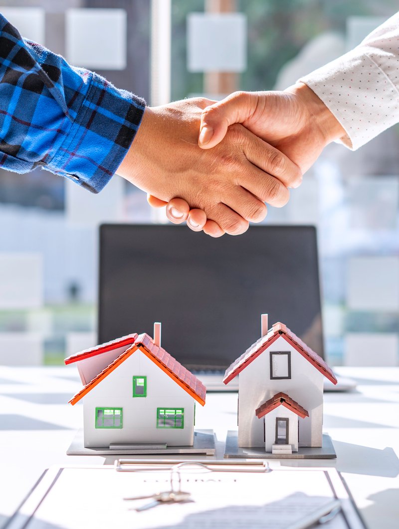 Real estate agents and clients shake hands and deliver the keys.